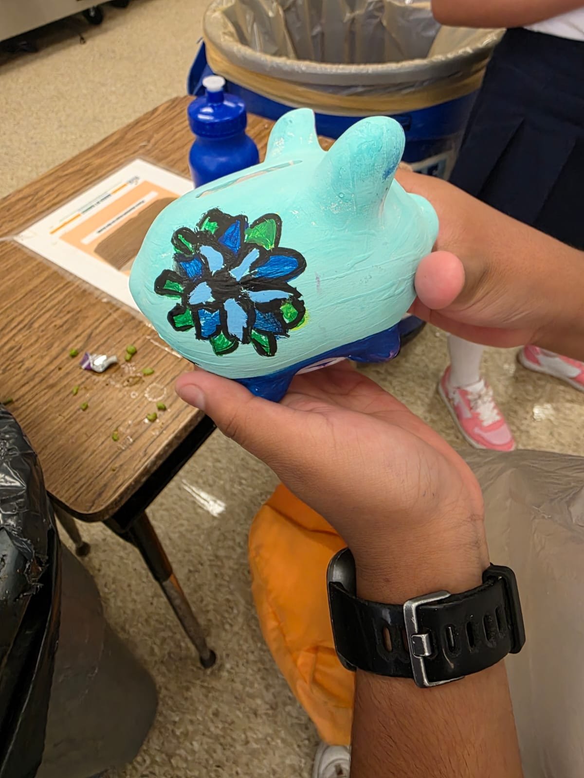 hands holding up light blue painted piggy bank